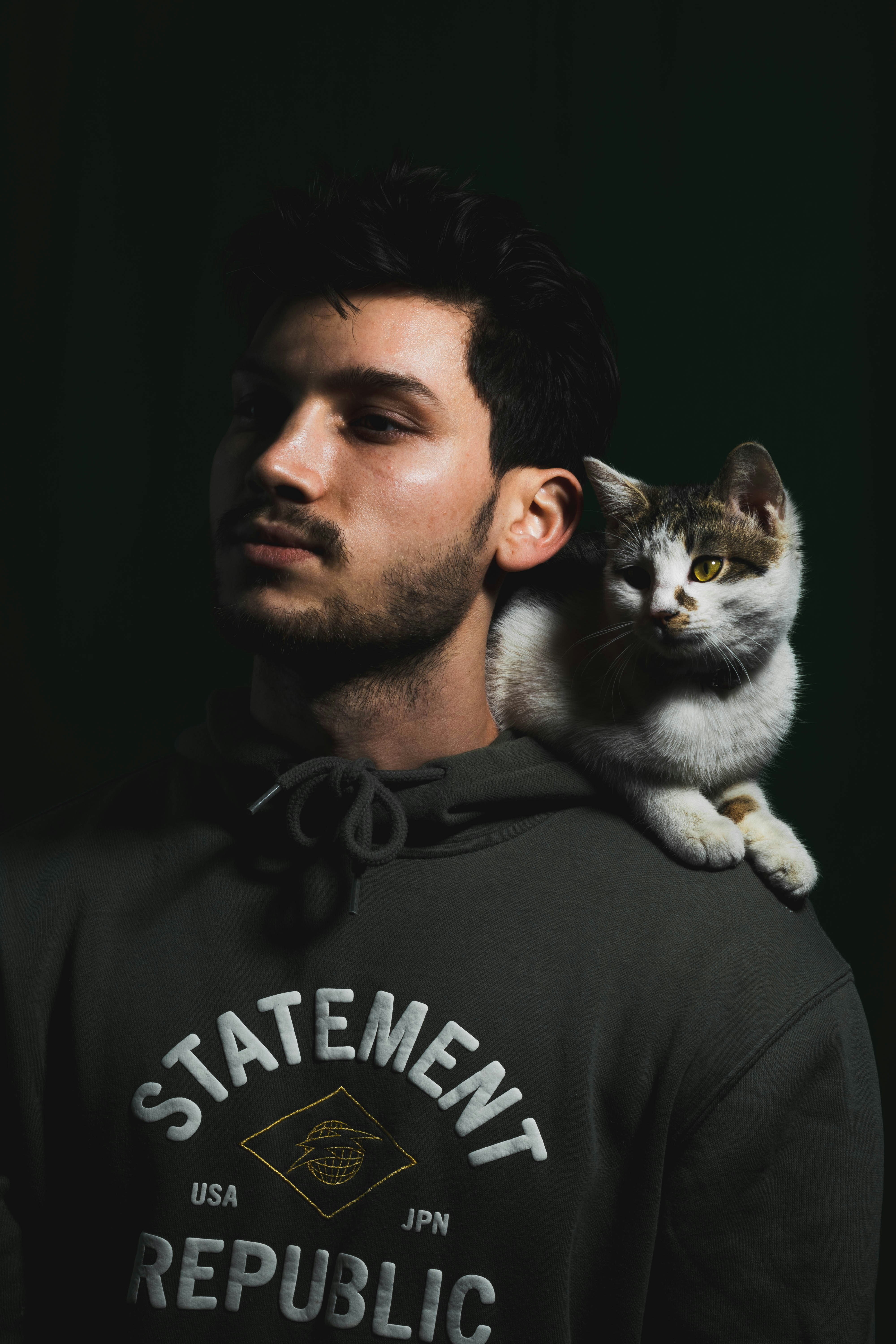 man in black and white crew neck shirt holding white and brown cat
